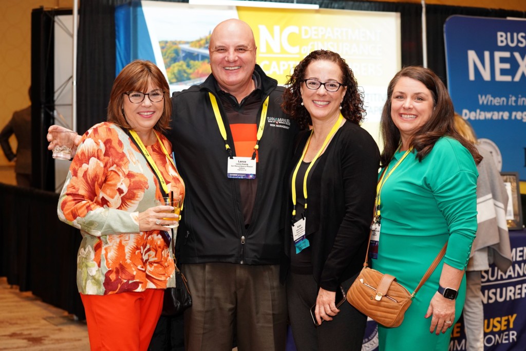 Four people in formal clothing smiling at the camera during a CICA 2023 International Conference networking event